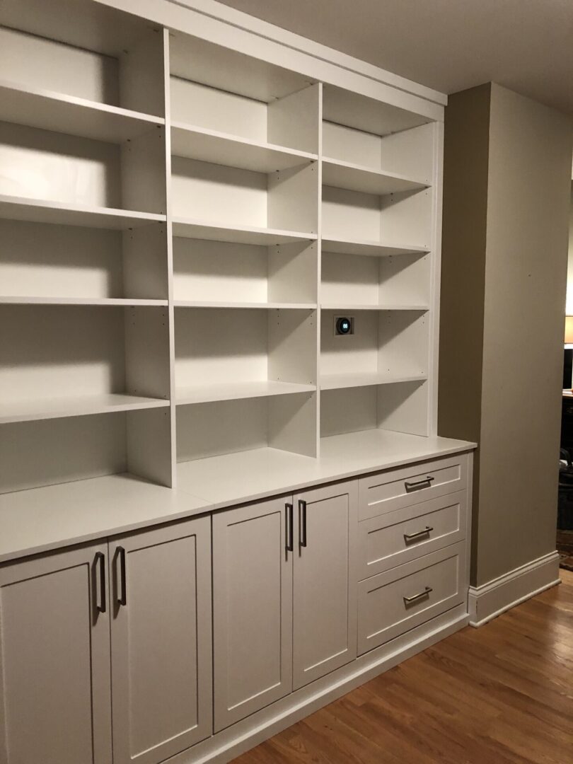 A white bookcase with drawers and shelves in it.