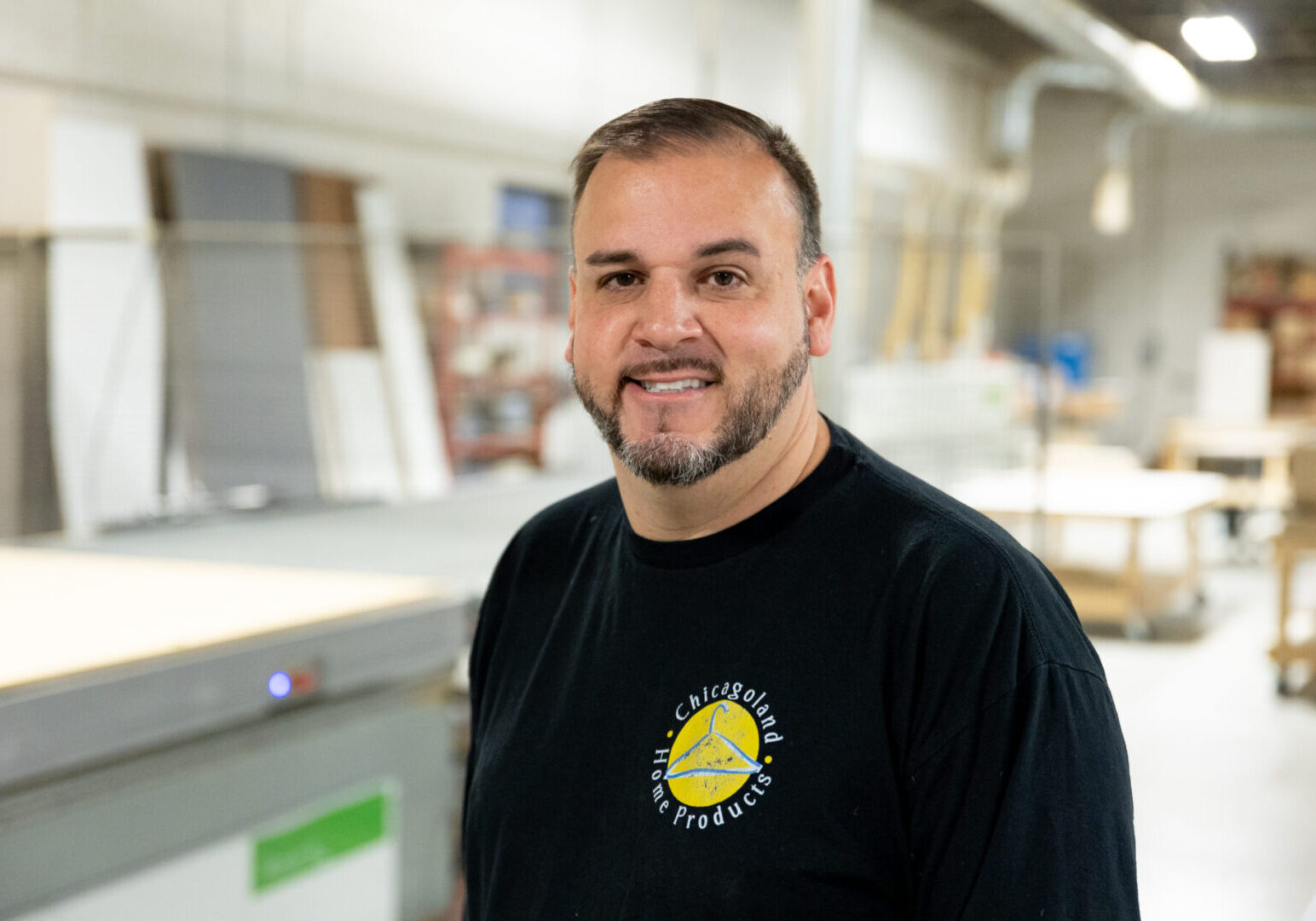 A man in black shirt standing next to a table.