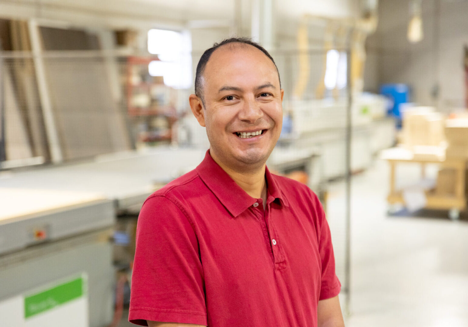 A man in red shirt standing inside of a kitchen.