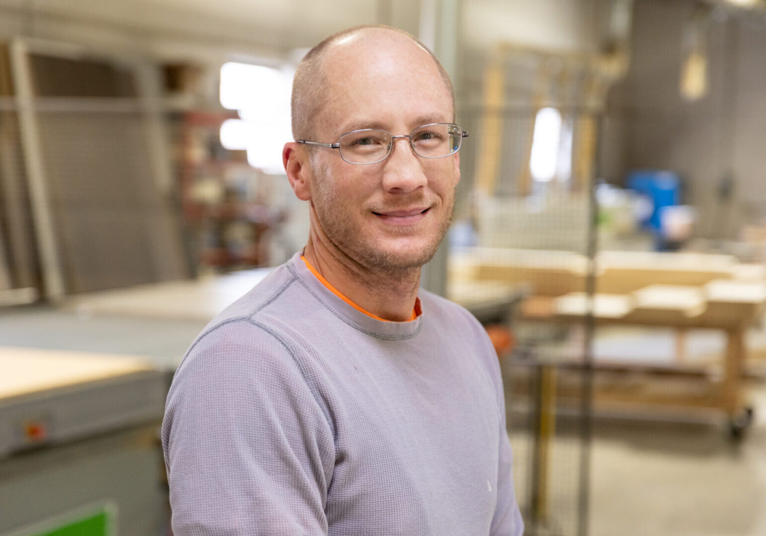 A man with glasses and bald head in a room.