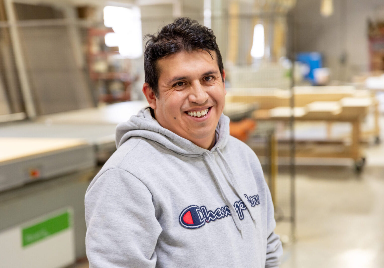 A man in a gray sweatshirt smiles for the camera.