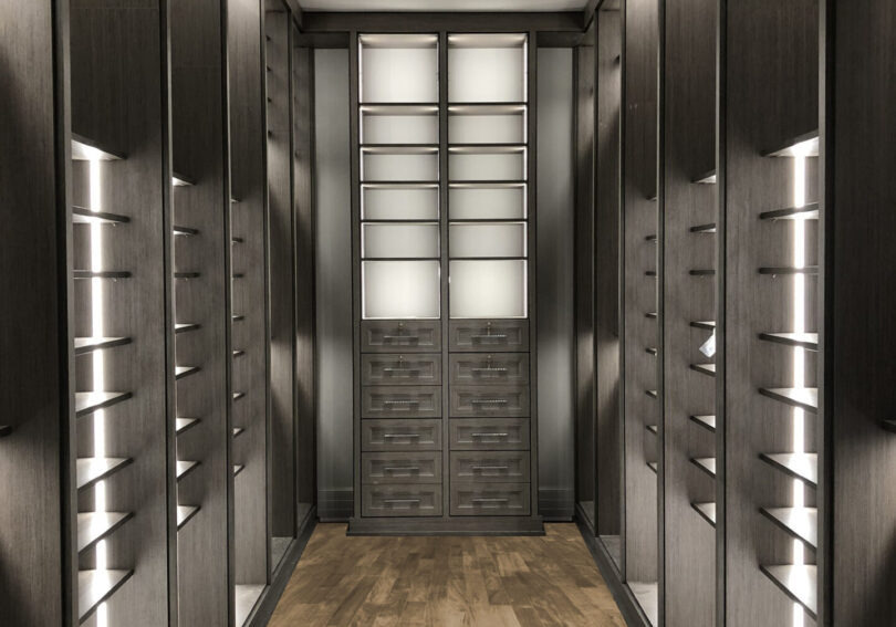 A walk in closet with many drawers and shelves.