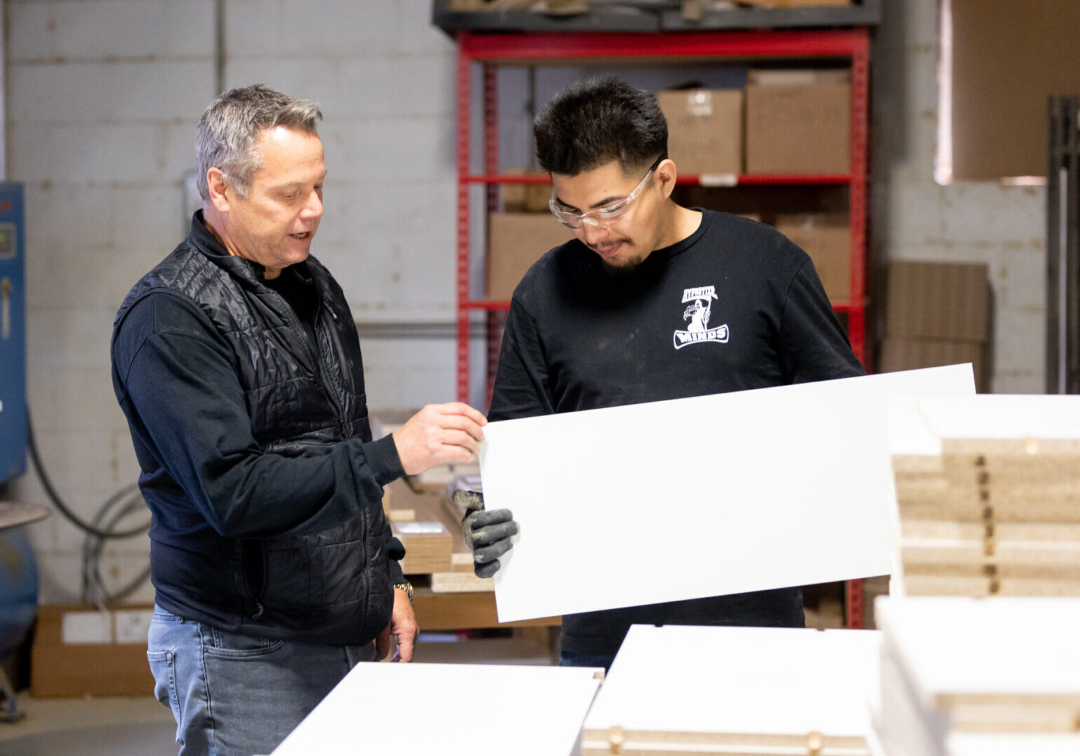 Two men are working together in a warehouse.